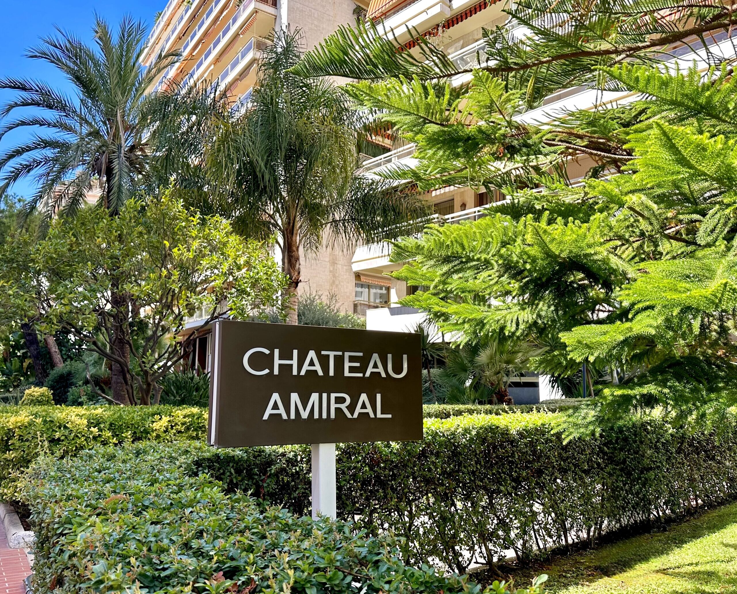 Chateau Amiral sign and the building behind it, surrounded by greenery